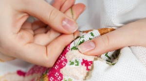 Woman hands doing cross-stitch. A close up of embroidery.