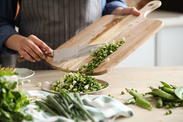 cooking chef is cutting greens in the kitchen - Заливной пирог с зелёным луком и яйцом