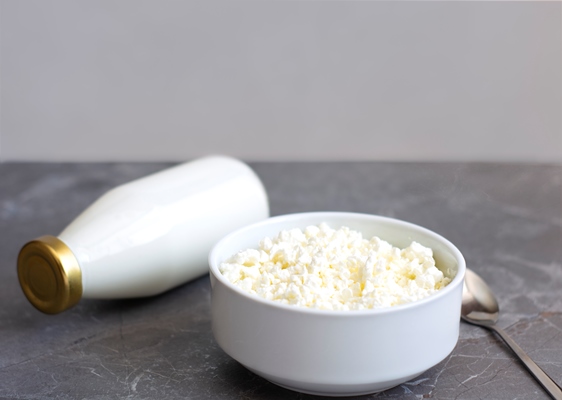 fresh natural cottage cheese in a white cup stands on a gray table - Низкокалорийная творожная пасха