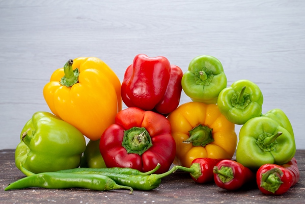 front view colorful bell peppers with peppers on the brown desk vegetable color - Овощи, бобовые, грибы: полезные советы