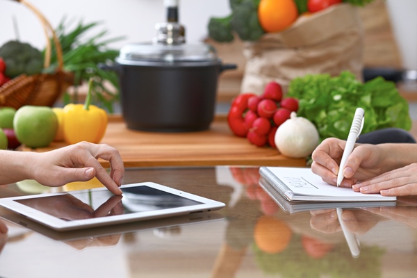 human hands of two female persons using touchpad for making menu in the kitchen closeup of two women are making online shopping by tablet computer and credit card cooking and shopping concept - Советы по выбору рецептов