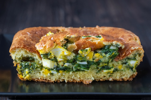 pouring pie with green wild garlic leaves and boiled eggs on wooden table close up - Заливной пирог с зелёным луком и яйцом