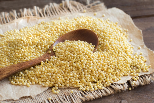 Как подготовить крупу к отвариванию raw millet with a spoon on wooden table close up - Как подготовить крупу к отвариванию