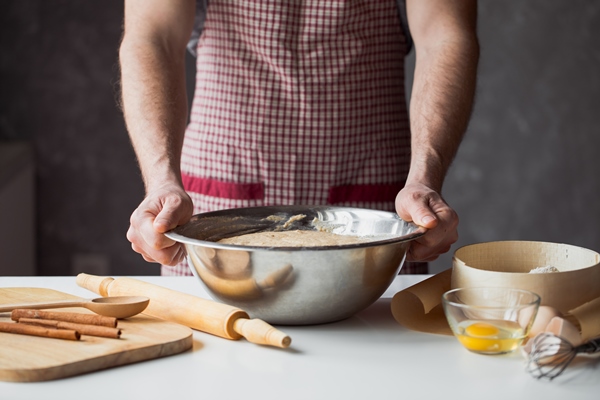 a handful of flour with egg on a rustic kitchen against the table of men s hands knead the dough - Кулич с апельсиновой цедрой