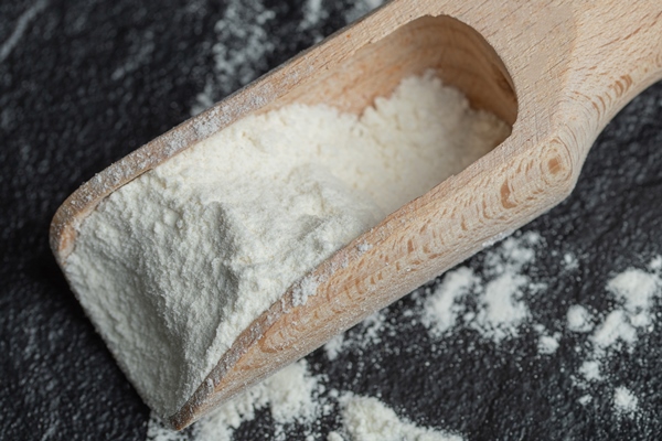 a wooden spoon with flour on black - Постные блинцы с какао