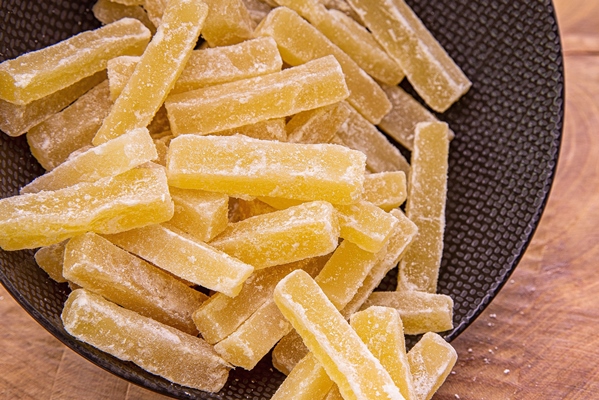 candied fruit poured from a dark cup onto a wooden table - Цукаты из кабачка