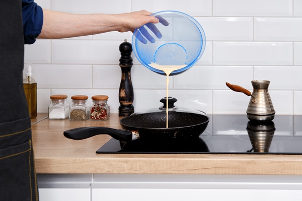 closeup view of pouring omelet on frying pan - Постные блинчики со сладкой морковью и изюмом