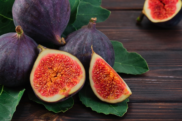 figs and halves of several fruits closeup on the leaves of a fig tree on an old wooden table horizontal frame seasonal fruits fig harvest background or mediterranean diet articles - Библия о пище