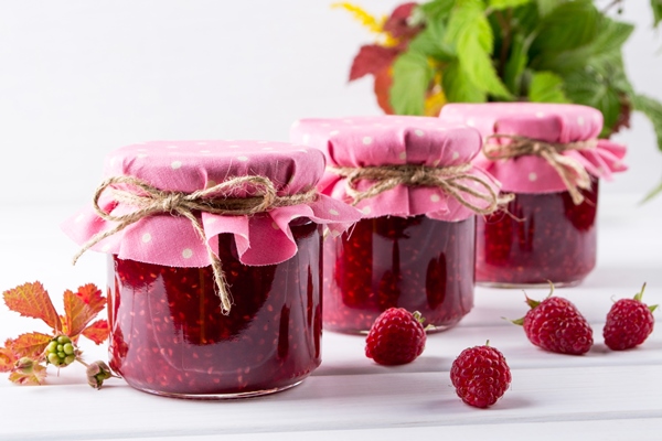Малина в собственном соку jars with raspberry jam placed in rows and fresh raspberry on white wooden table - Малина в собственном соку