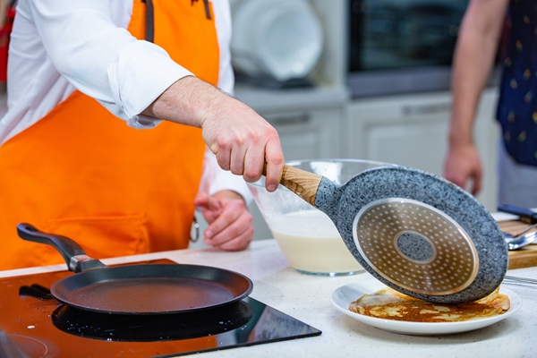 kitchen preparation the chef in a bright apron fries fresh pancakes in two pans 1 - Постные блинчики с карамельным яблоком