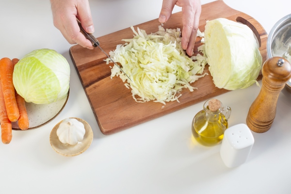 man cutting cabbage in the kitchen at home - Борщевая заправка на зиму