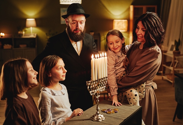 portrait of modern jewish family looking at silver menorah candle during hanukkah celebration in coz - Библия о пище