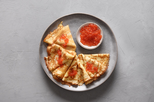 russian thin pancakes with red caviar on grey background - Постные блины с "икрой" из ламинарии