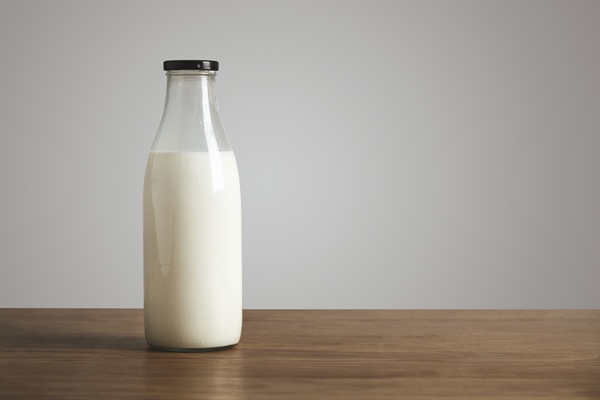 simple vintage bottle filled with fresh milk on thick wooden table closed with black cap cafe shop - Кулич бабушкин