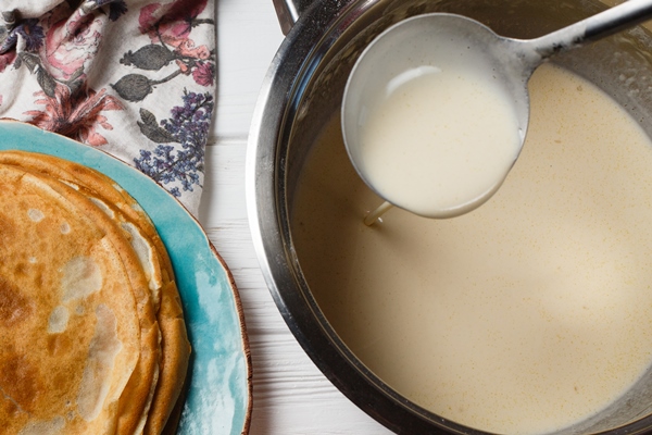 the process of making traditional thin pancakes pancakes and a bowl with a test on the table - Постные блинчики с рыбным "припёком"