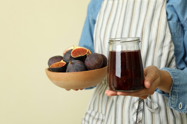 Библия о пище woman in apron holds jar of fig jam and bowl with fig - Библия о пище