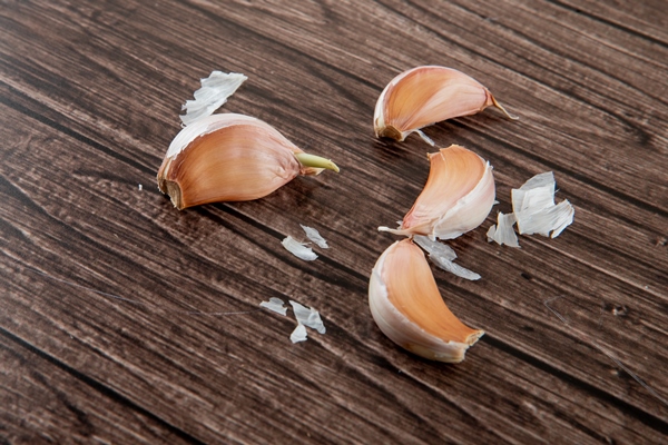 close up view of garlic cloves with skin on wooden background with copy space - Соус "Сацебели"