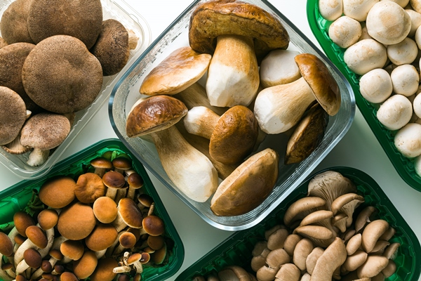 different types of fresh mushrooms in plastic packaging isolated on white table - Постная картофельно-грибная запеканка с креветками