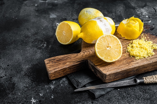 grated lemon zest and spiral peel on wooden board black background top view copy space - Салат "Южный"