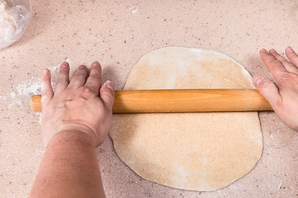hands flatten sheet of dough by wooden rolling pin - Рулет с укропом