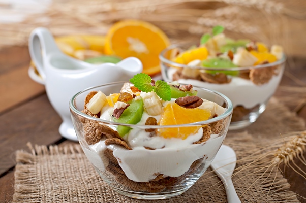 healthy dessert with muesli and fruit in a glass bowl on the table - Мюсли с йогуртом и соком