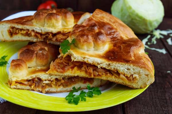 Пирог со свежей капустой homemade pie with cabbage chopped pieces on a dark wooden background close up - Пирог со свежей капустой
