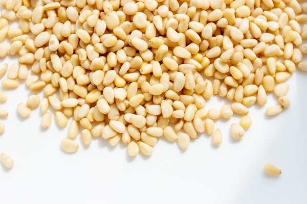 peeled dried pine nuts on white background - Зелёная фасоль с орехами