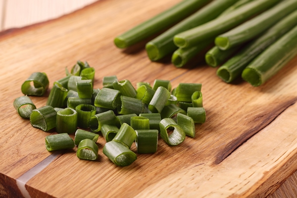 pile of chopped green onion with onion stalks on wooden board - Зелёный лук по-гречески