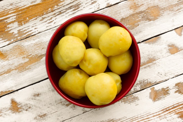 purified boiled yellow potatoes in a red bowl on the old wooden table - Постная запеканка с картошкой и грибами