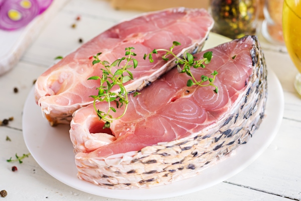 raw steak of carp fish with lemon and thyme on white wooden surface preparing fish for roasting in parchment paper diet menu - Карп жареный или печёный