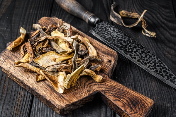 sliced porcini wild dried mushrooms on a wooden cutting board black wooden background top view - Постный суп грибной с картофелем