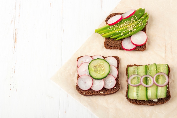 Бутерброды с авокадо, постный стол superfood open vegetarian sandwich with different toppings avocado cucumber radish on a paper on white background healthy eating organic and veggie food - Бутерброды с авокадо, постный стол