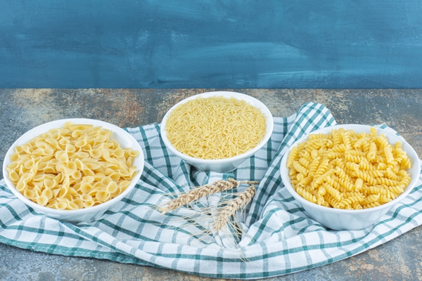 three bowls of pasta next to two wheat on the towel on the marble background - Суп грибной, постный стол