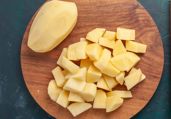 top view sliced fresh potatoes peeled out vegetables on dark blue background - Постный грибной суп с сухофруктами