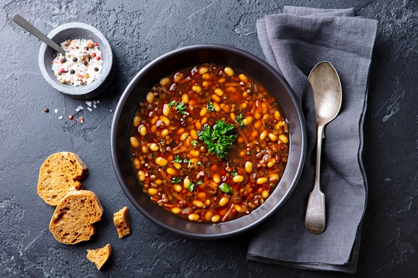 bean soup in a black bowl dark background top view - Суп острый из красной фасоли с орехами