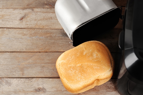 bread machine with loaf on wooden table - Овсяный хлеб дрожжевой