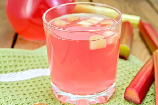 compote from rhubarb in glassful and jug with sugar on board - Квас из ревеня