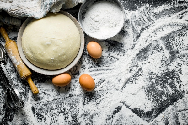 dough in bowl with eggs rolling pin and flour - Славский колач