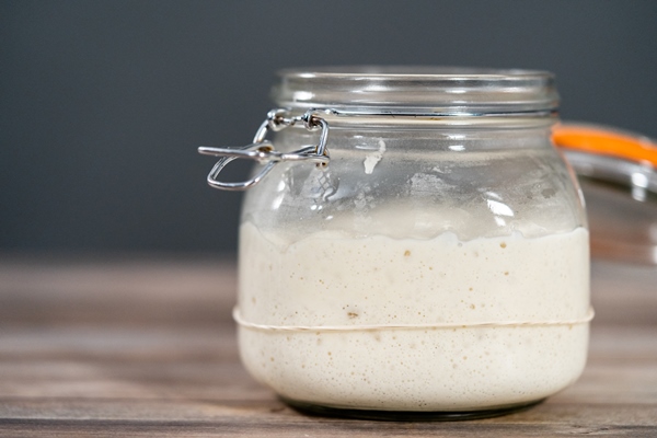 feeding sourdough starter in a glass mason jar for baking artisan bread - Квас боярский