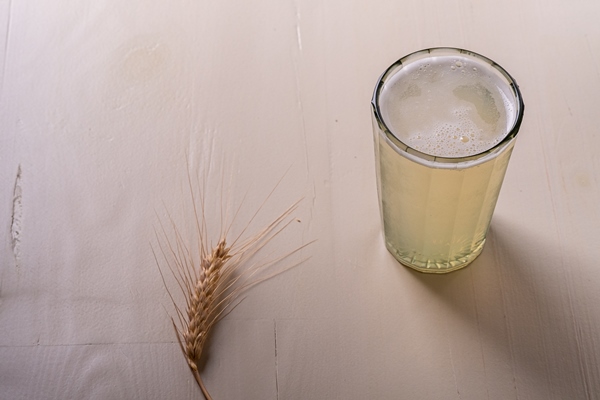 Квас с дрожжами (болгарский рецепт) fresh cold drink beverage frothy kvass in faceted glass on white wooden wall near with ear of wheat - Квас с дрожжами (болгарский рецепт)