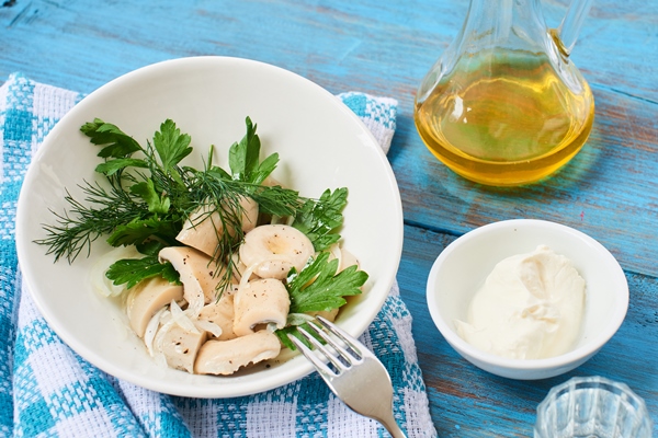 salted mushrooms in a white plate a bowl of sour cream and a jug of oil on a wooden table - Солёные волнушки (холодный способ)