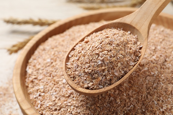 spoon of wheat bran above bowl closeup - Алёнин квас на отрубях