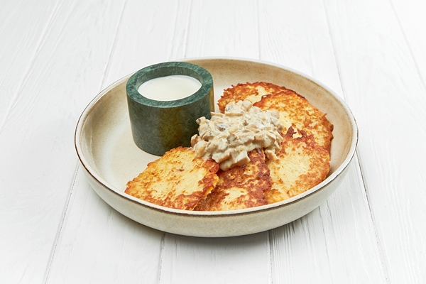 Драники с шампиньонами ukrainian potato draniki or hash browns in a plate on a white wooden background - Драники с шампиньонами