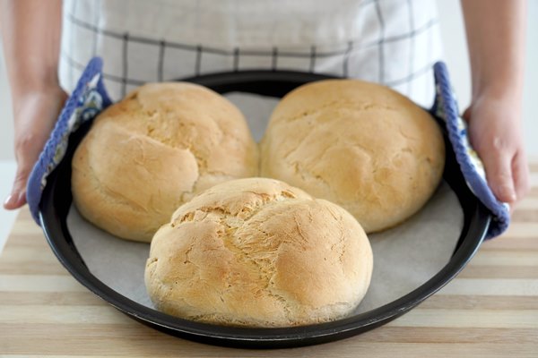 woman showing three homemade loaves of bread in baking tray freshly baked - Домашние городские булки