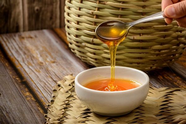 bee honey and spoon in white bowl over wooden table - Постный салат с мандаринами