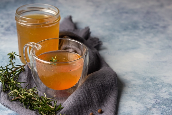 bone or vegetable broth bouillon in a glass mug and aromatic herbs - Минестроне, постный стол