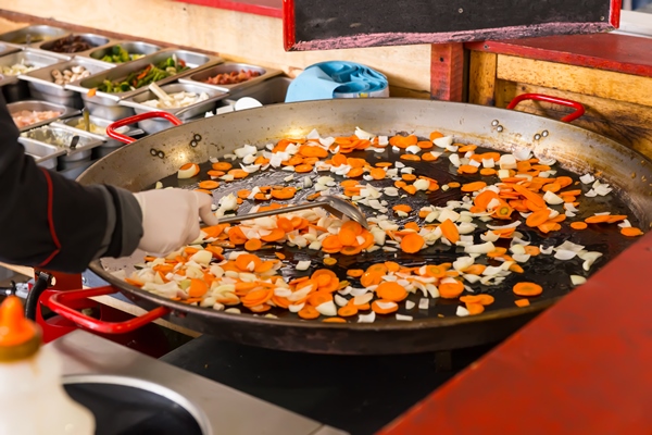 cook stir frying fresh vegetables in a large pan on a buffet moving the diced veggies with a spatula - Минестроне, постный стол