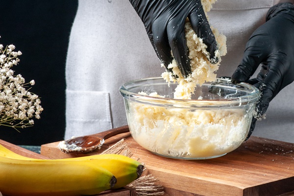 front view female cook making coconut candies from condensed milk on dark background - Постное кокосовое печенье