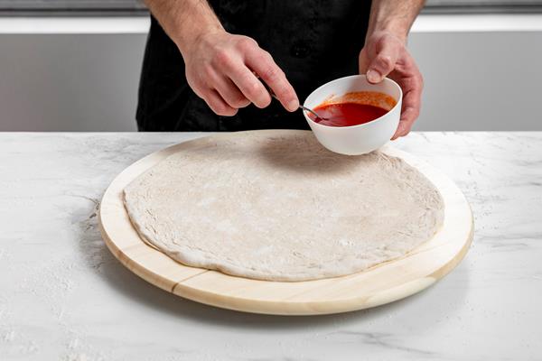 high angle man spreading tomato sauce on pizza dough - Постная пицца с грибами и овощами