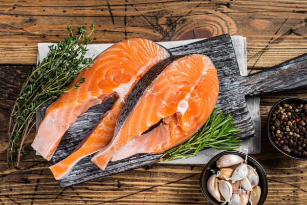 raw salmon steaks on a wooden cutting board with thyme and rosemary wooden background top view - Сёмга, запечённая с луком и картофелем, постный стол